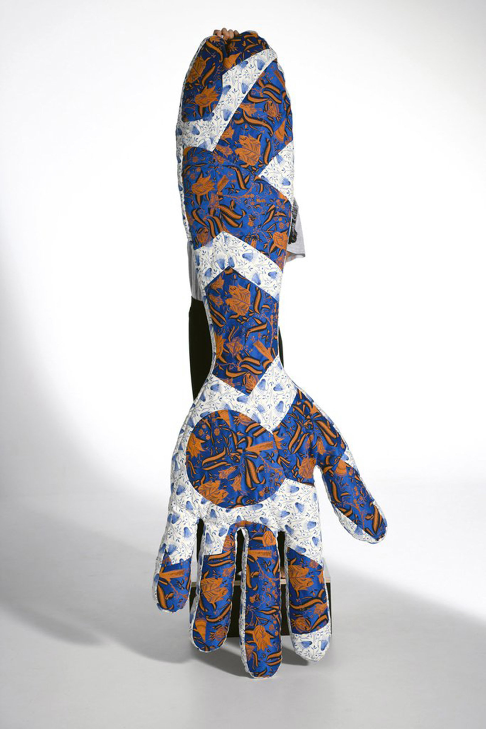 Bolster in Handform, mit hellblau, dunkelbau, organem Muster, wird von einer Person hochgehalten, diese vom Bolster verdeckt